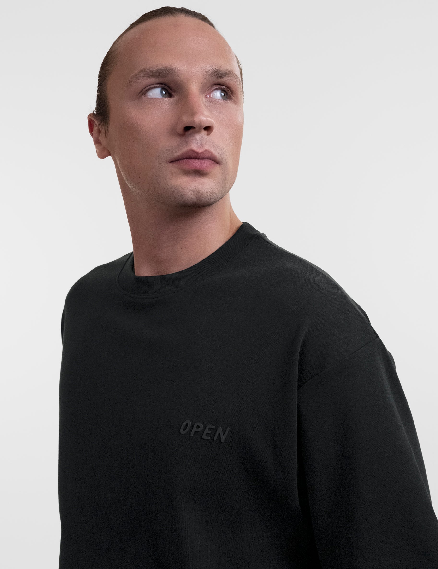 Open Row Men's Open Heart Tee in black, front three-quarter closeup view, embossed logo detail.