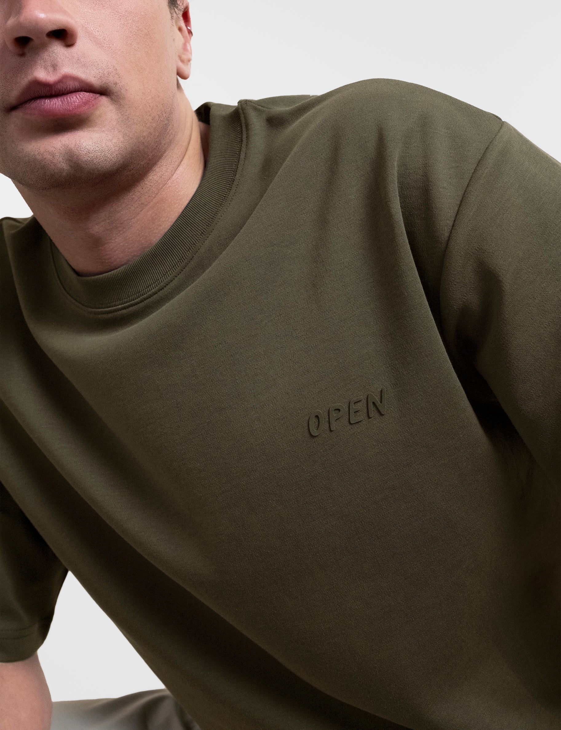 Open Row Men's Open Heart Tee in khaki green, close up view, embossed logo detail.