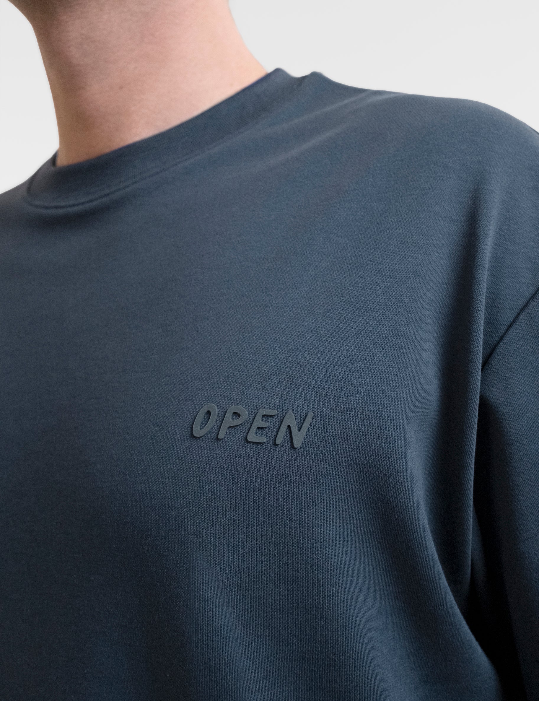 Open Row Men's Open Heart Tee in navy blue, closeup view, embossed logo detail.
