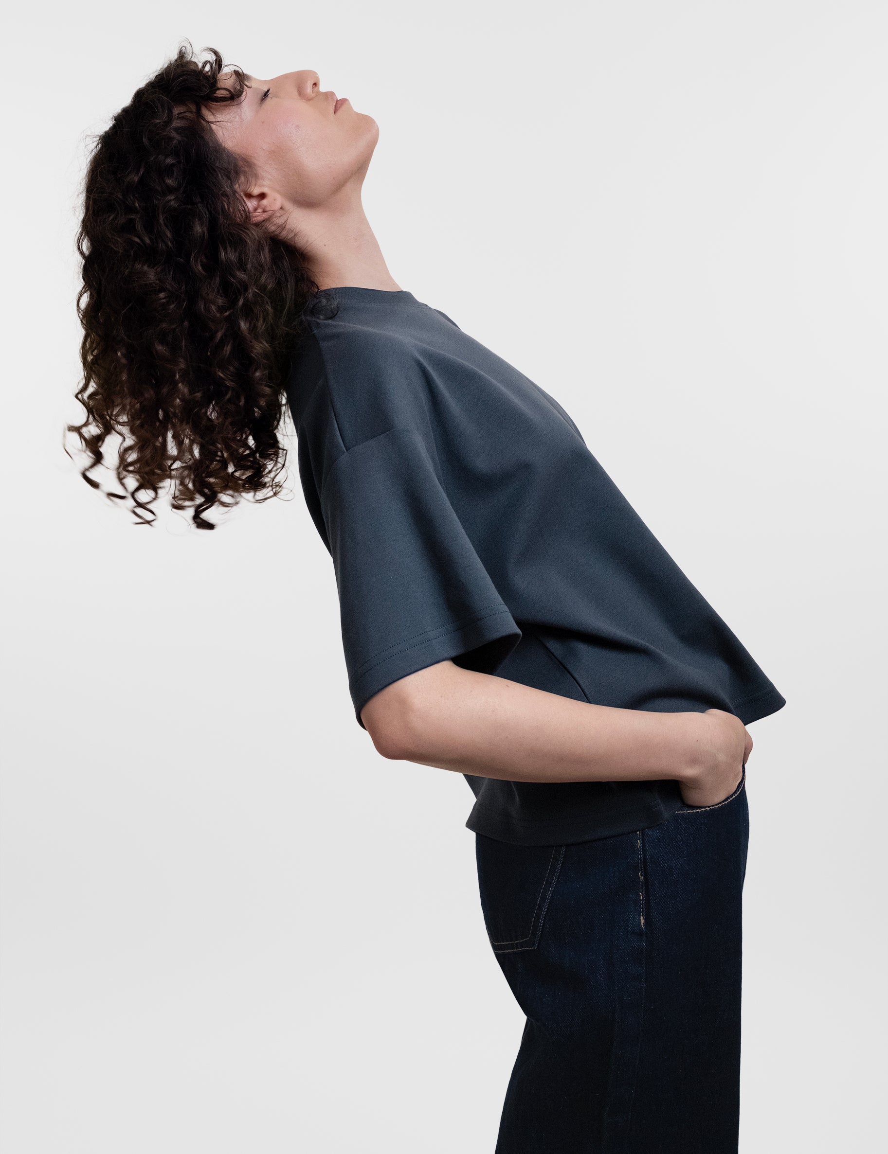 Open Row Women's Open Heart Tee in navy blue, side view, model arching backwards.