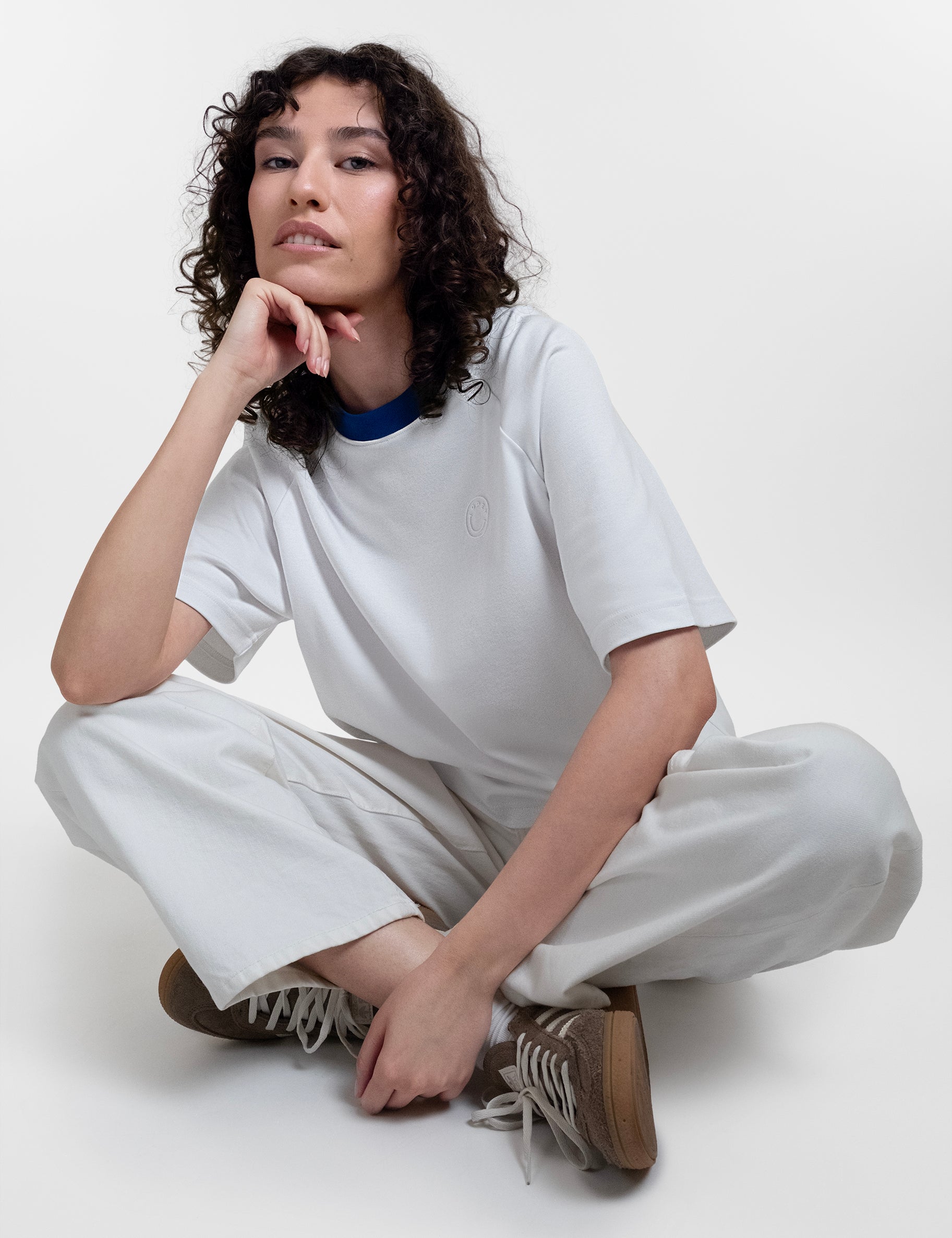 Open Row Women's Runaway Tee in white with blue collar, editorial view paired with white pants.