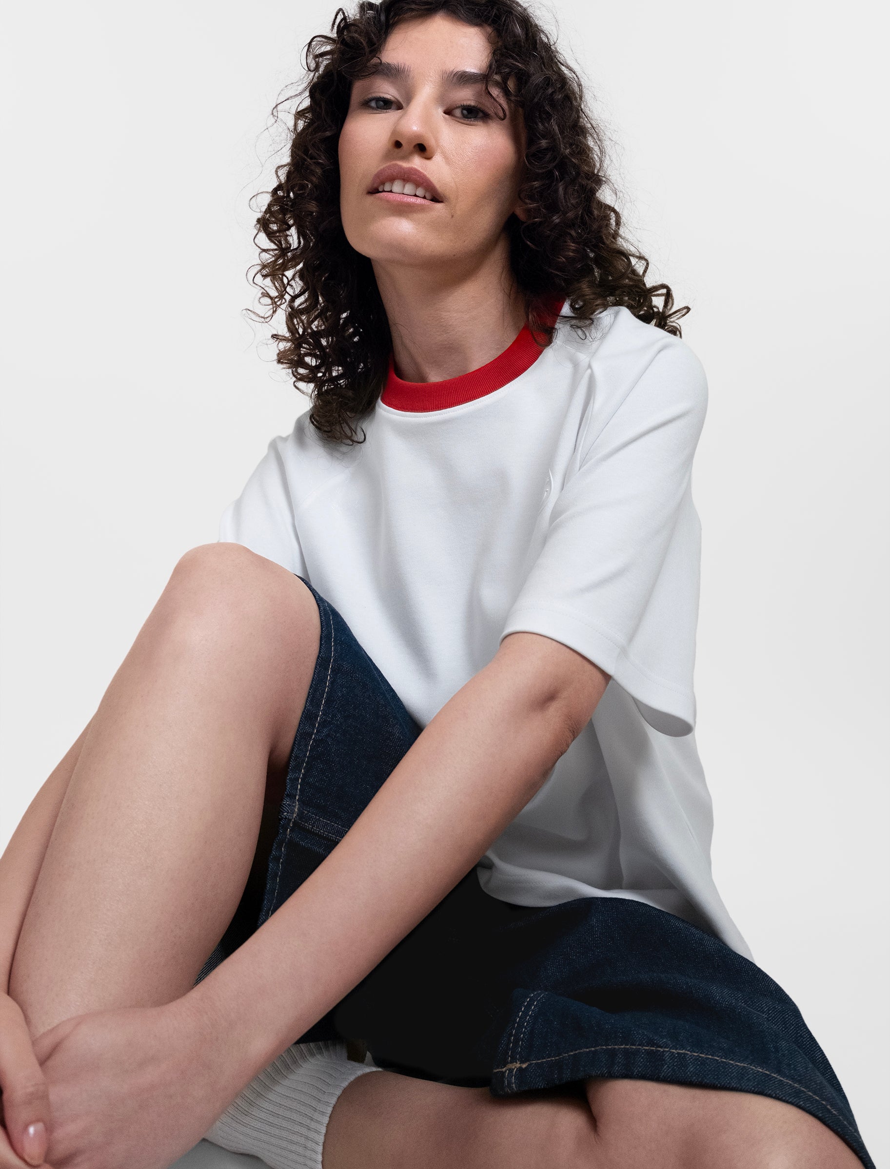 Open Row Women's Runaway Tee in white with red collar, sitting editorial view paried with denim shorts.
