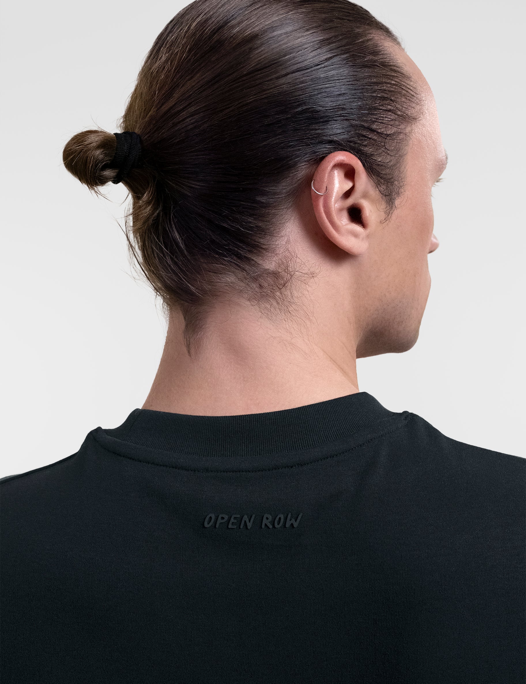 Open Row Men's Tank Tee in black, closeup view, embossed logo detail.