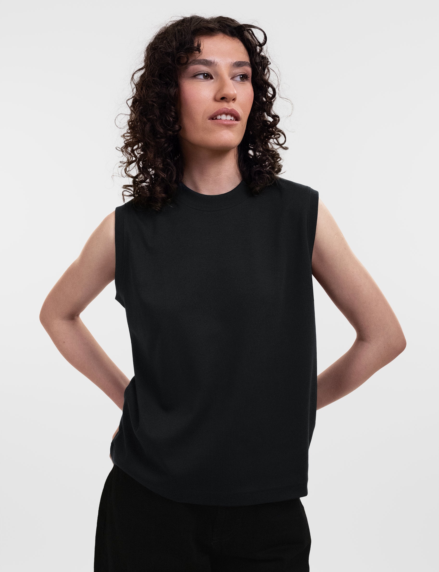 Open Row Women's Tank Tee in black, front view, model looking to the side with arms behind her back.