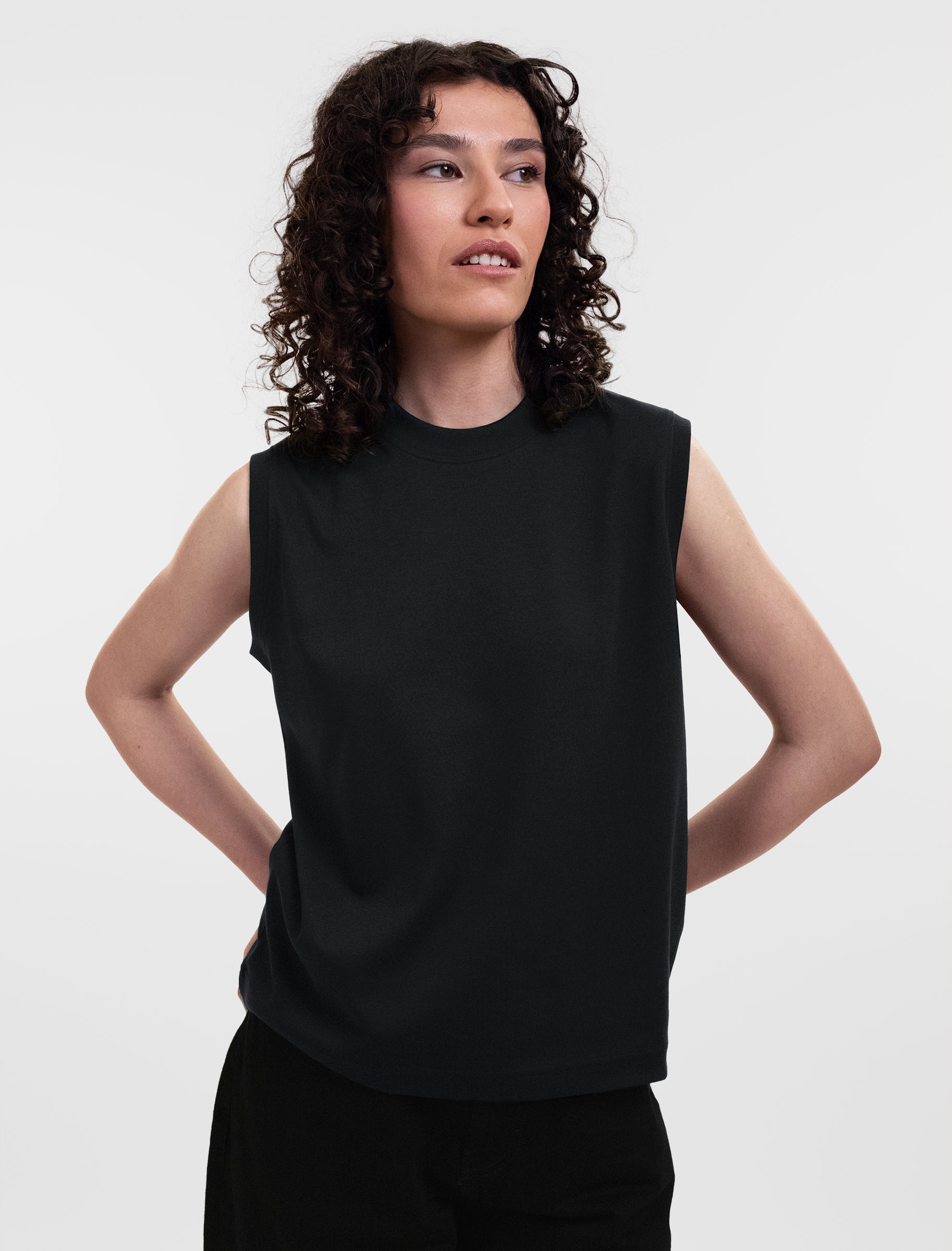 Open Row Women's Tank Tee in black, front view, model looking to the side with arms behind her back.