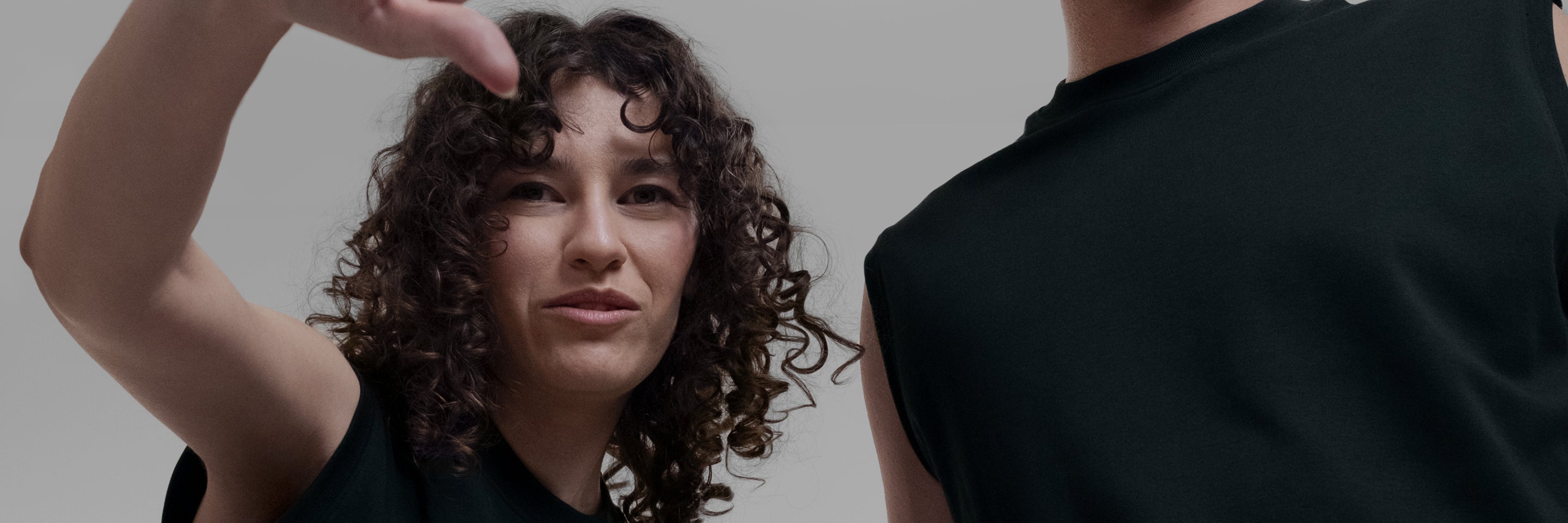 Two models wearing black Open Row Tank Tees against a plain light gray studio background.