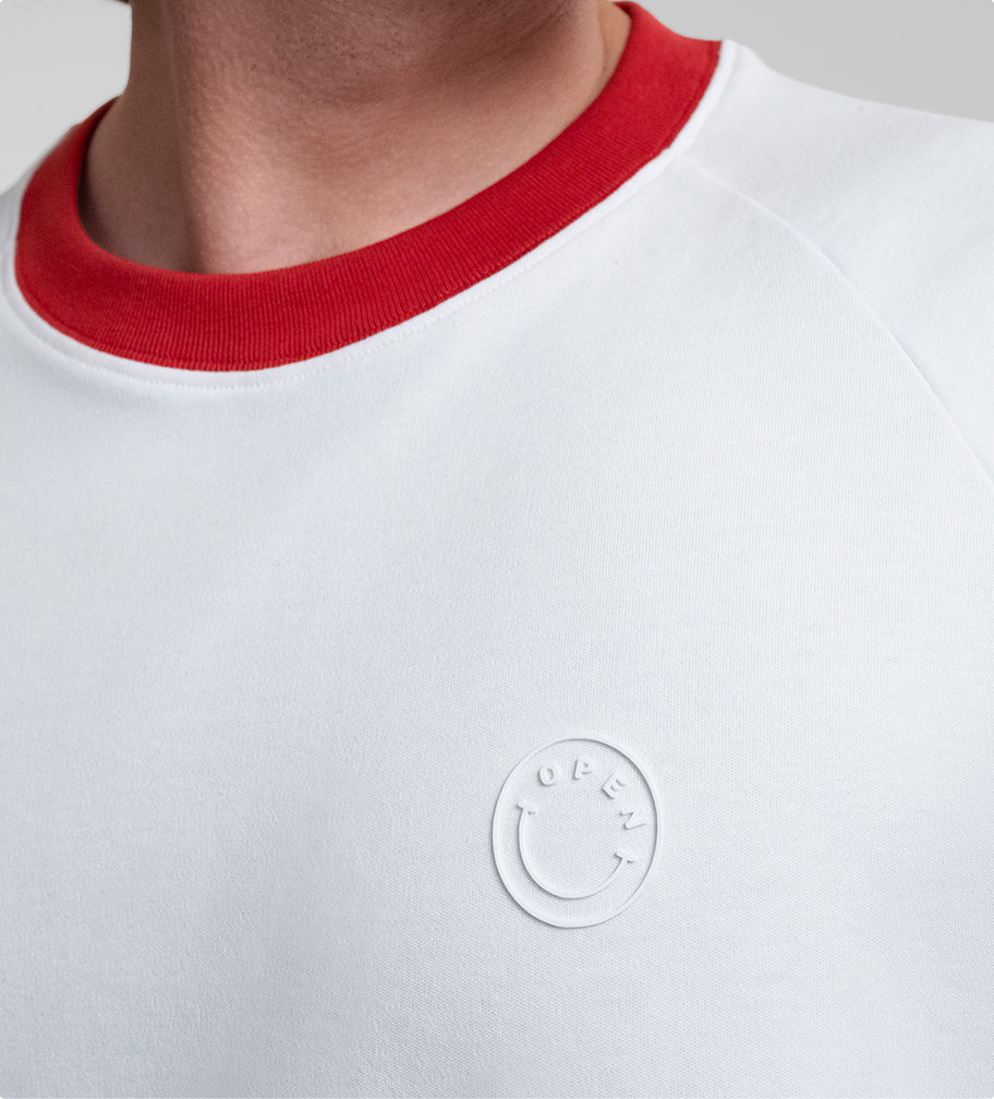 Close-up of a male model wearing a white Runaway Tee with red collar and a small white circular logo reading "OPEN" on the chest.