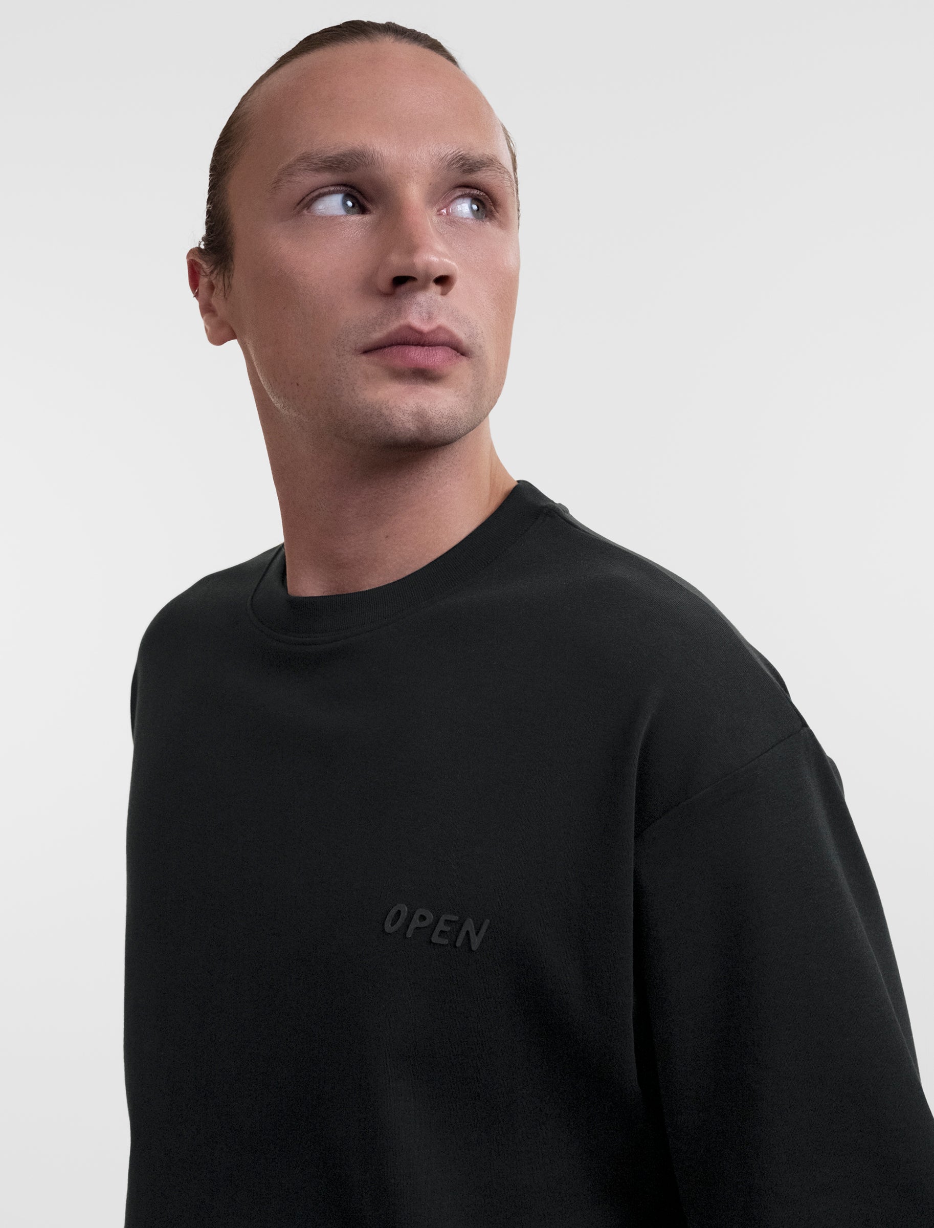 Open Row Men's Open Heart Tee in black, front three-quarter closeup view, embossed logo detail.