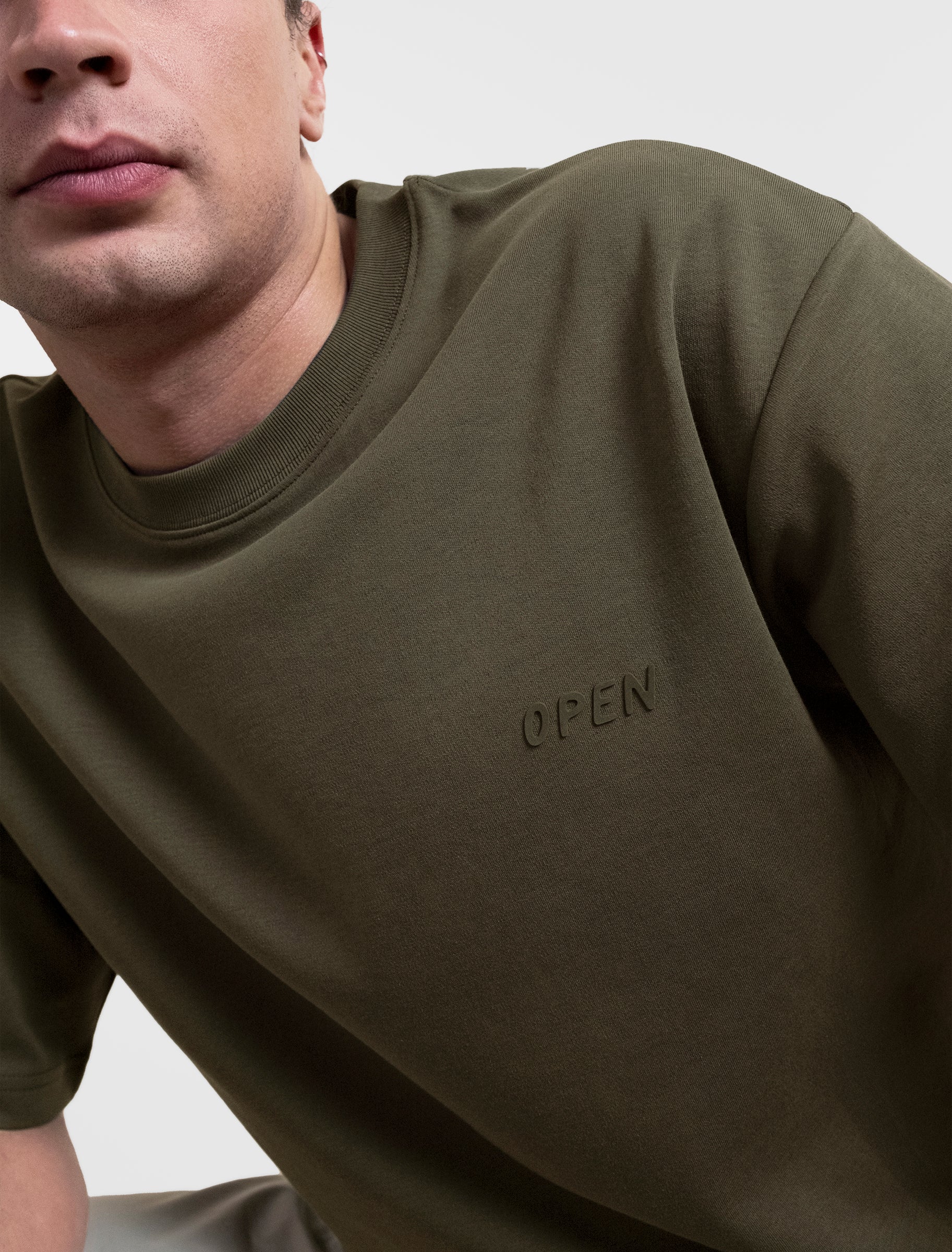 Open Row Men's Open Heart Tee in khaki green, close up view, embossed logo detail.
