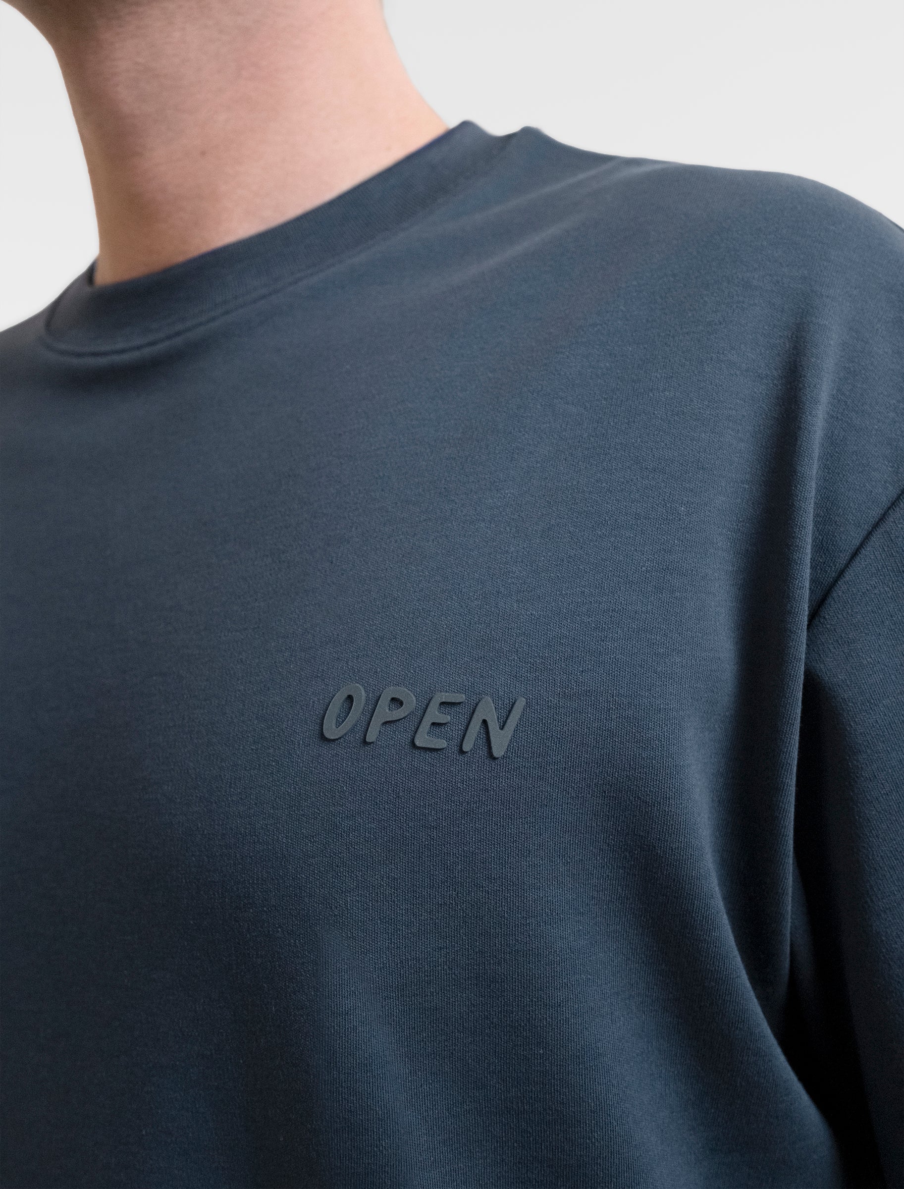Open Row Men's Open Heart Tee in navy blue, closeup view, embossed logo detail.