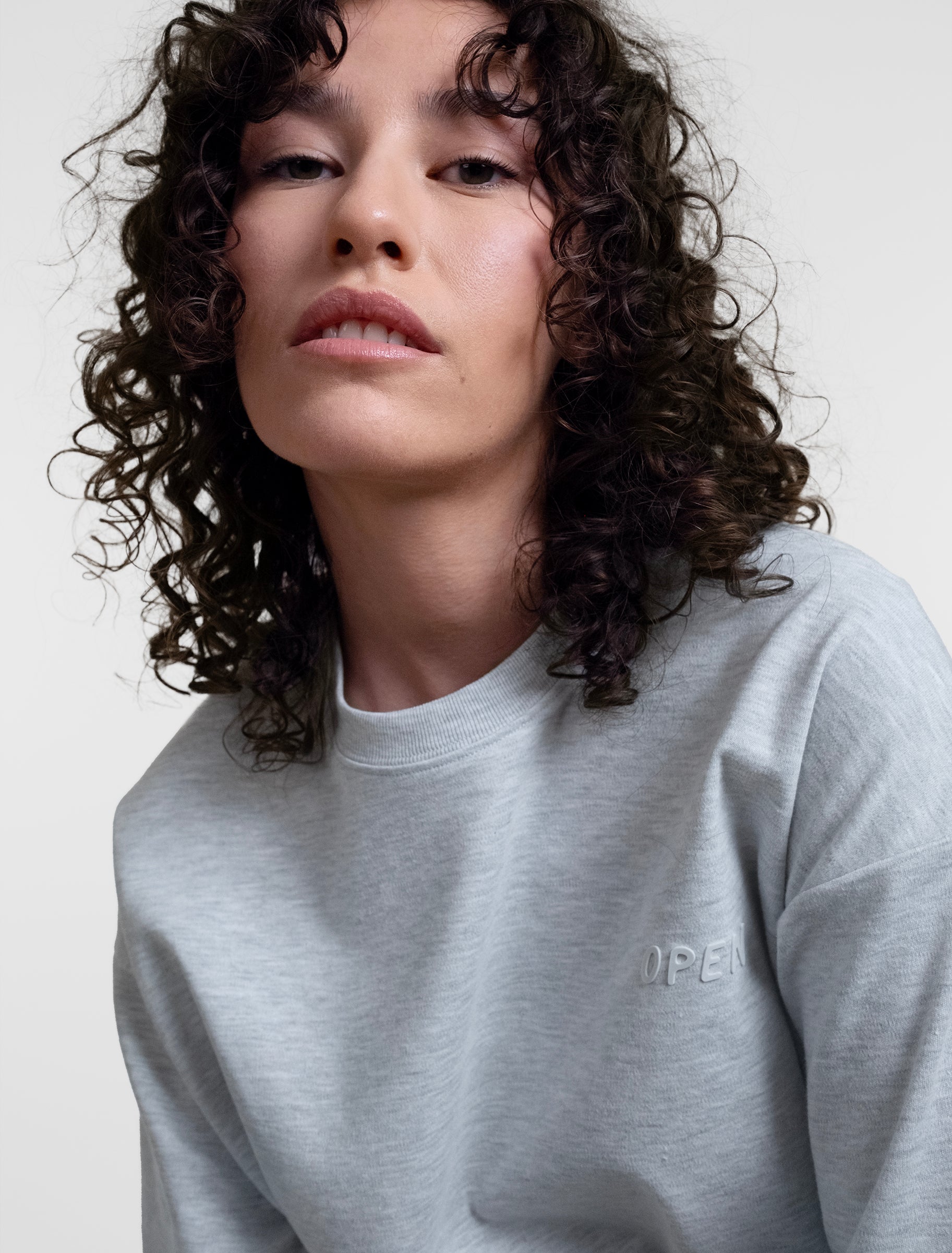 Open Row Women's Open Heart Tee in grey, closeup view, embossed logo detail.