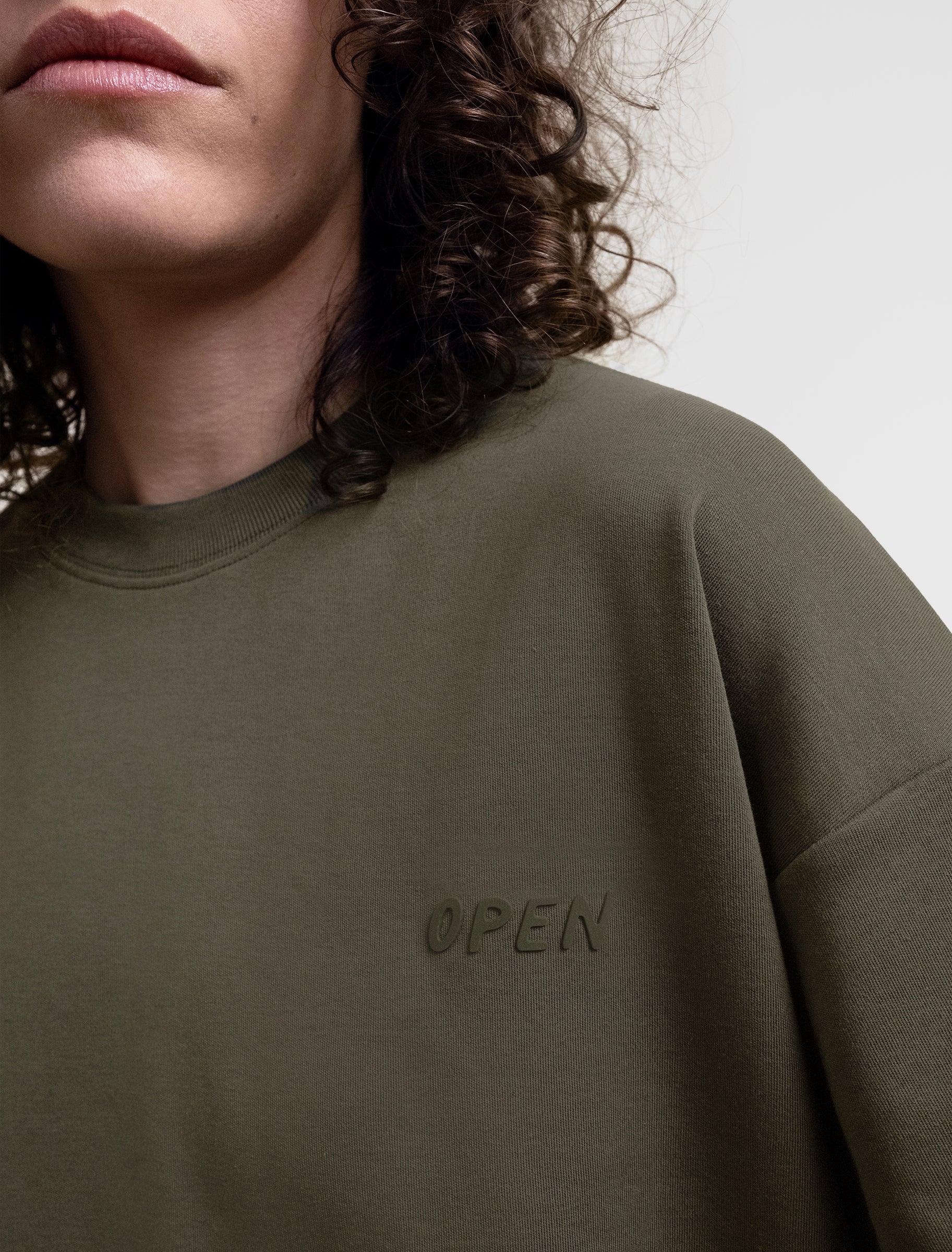 Open Row Women's Open Heart Tee in khaki green, closeup view, embossed logo detail.