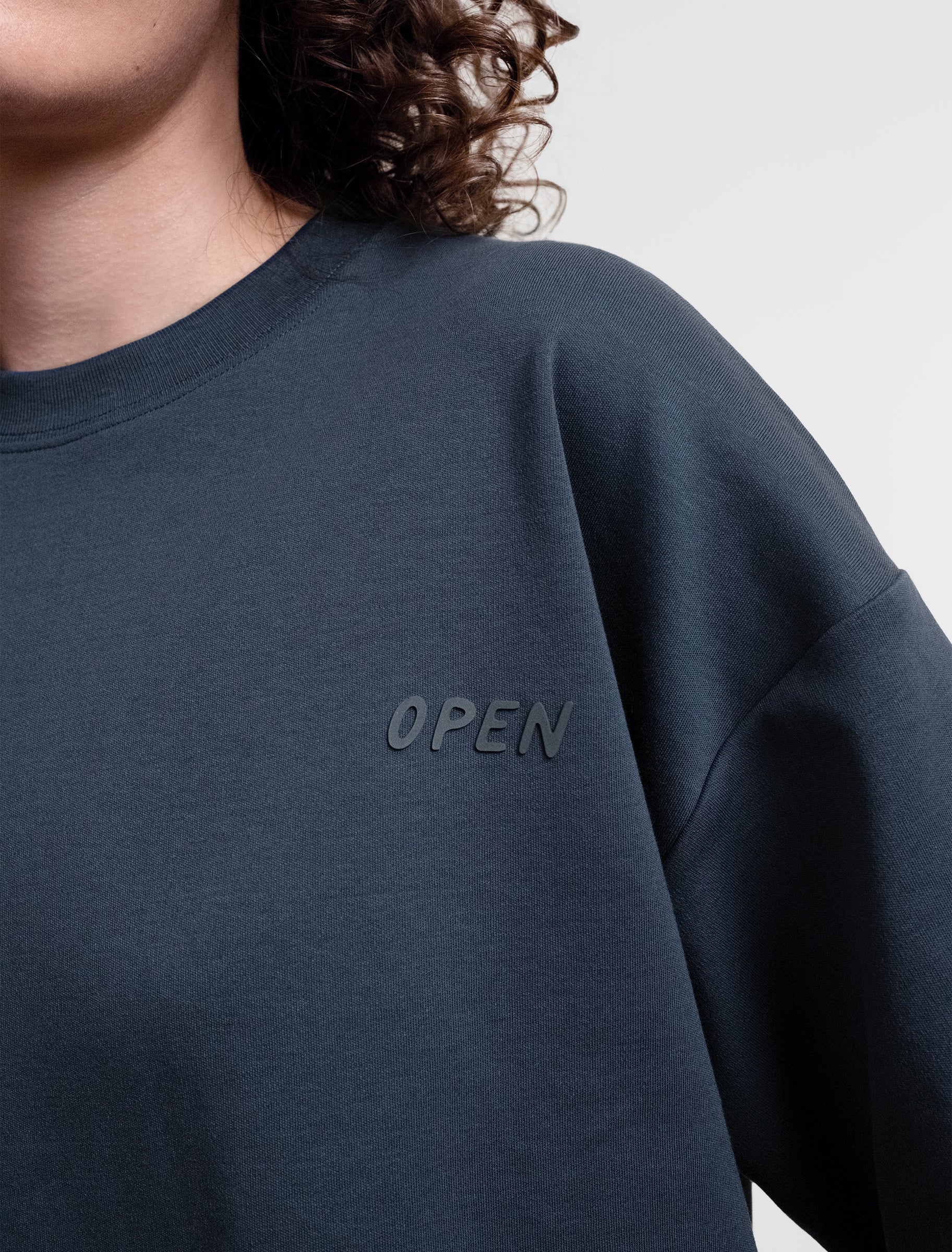 Open Row Women's Open Heart Tee in navy blue, closeup view, embossed logo detail.