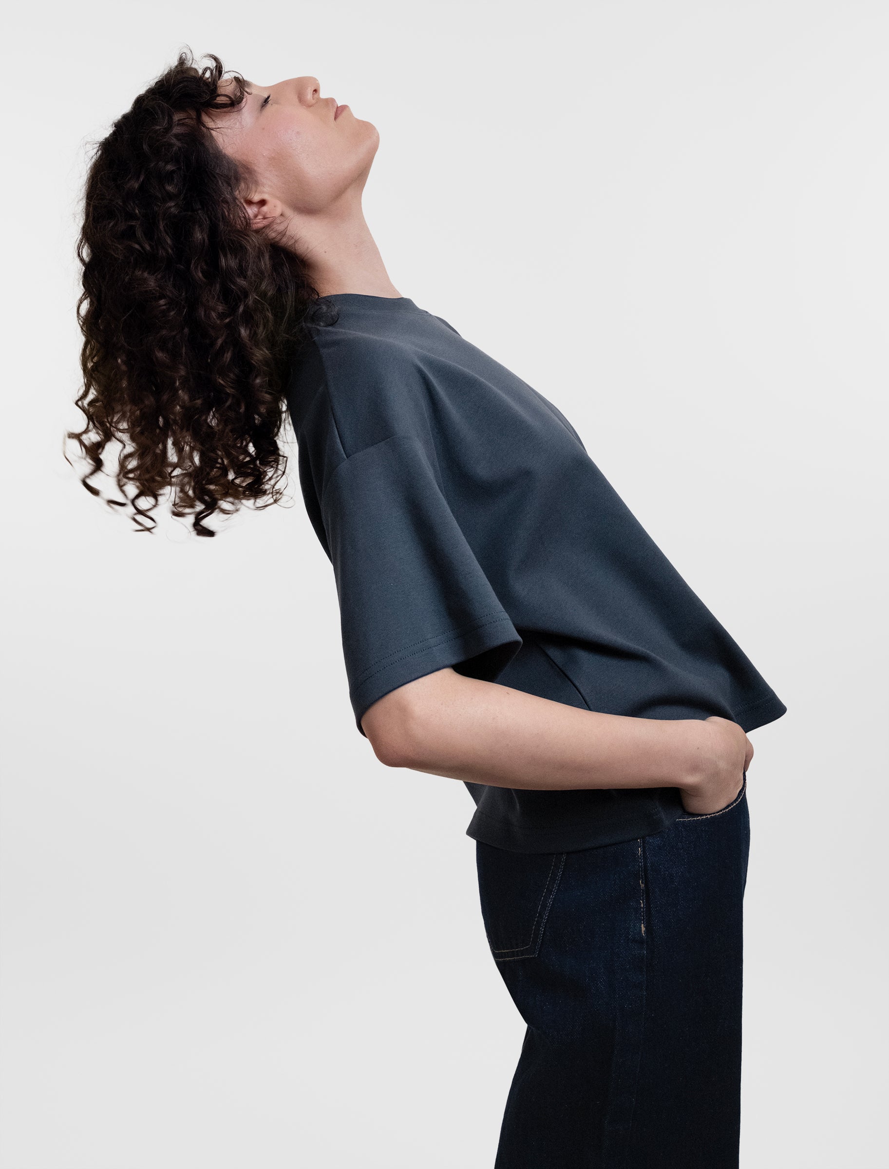 Open Row Women's Open Heart Tee in navy blue, side view, model arching backwards.