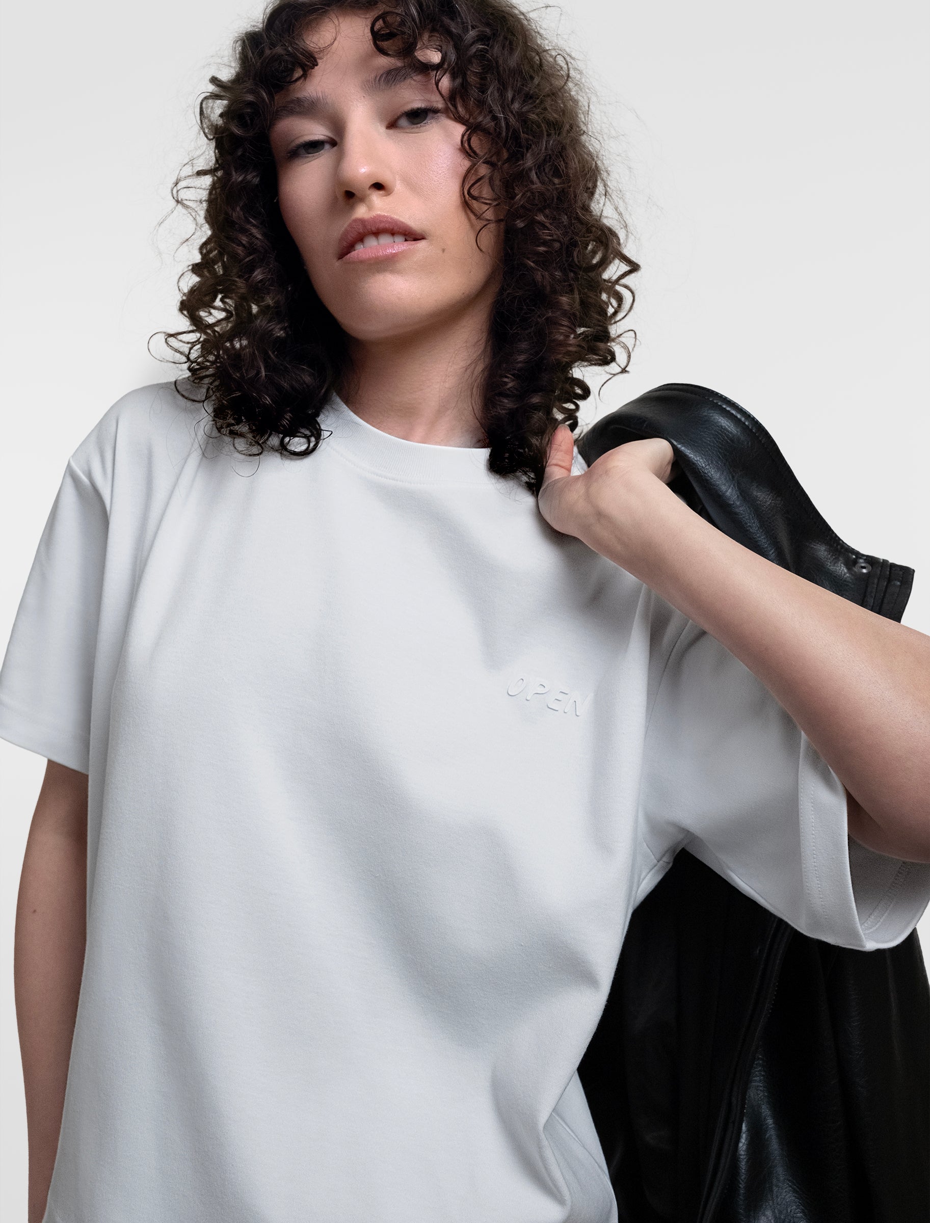 Open Row Women's Open Heart Tee in white, front editorial view paired with a black leather jacket.