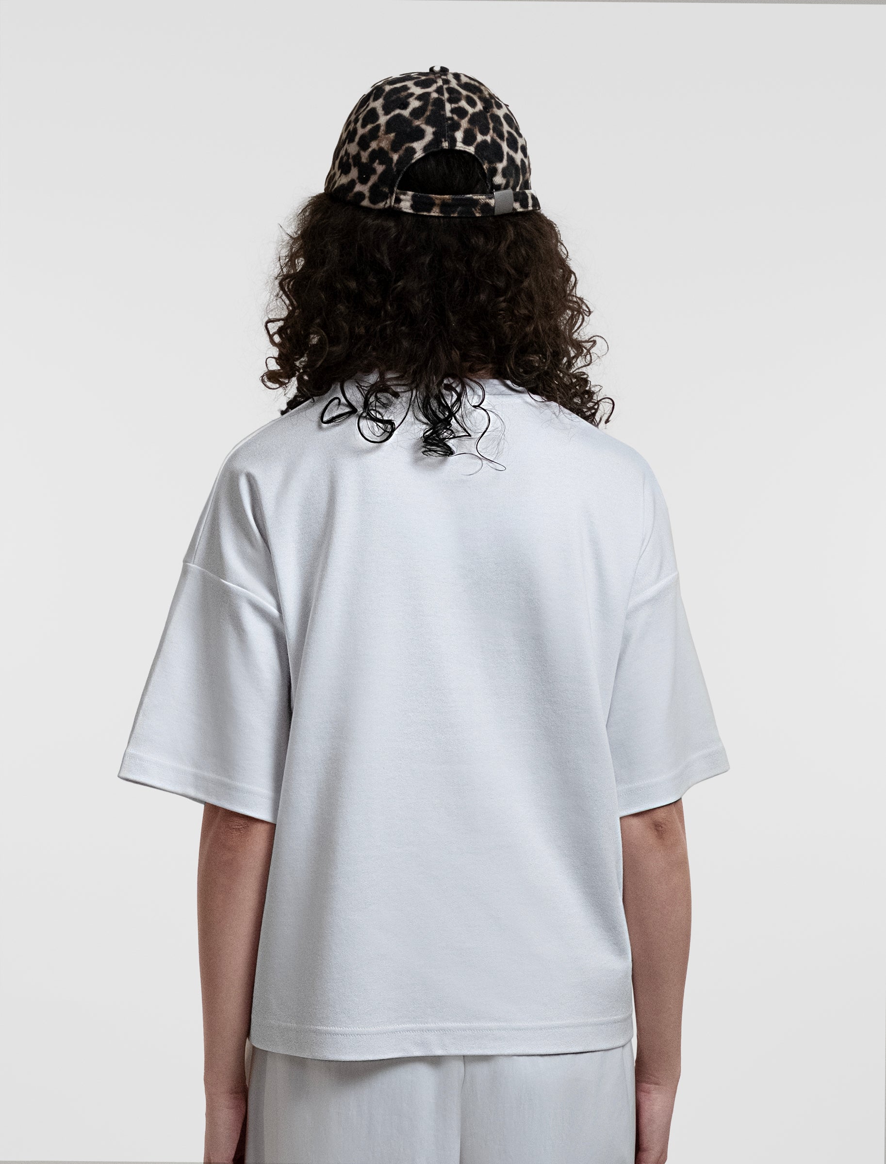 Open Row Women's Open Heart Tee in white, back view paired with a baseball cap.