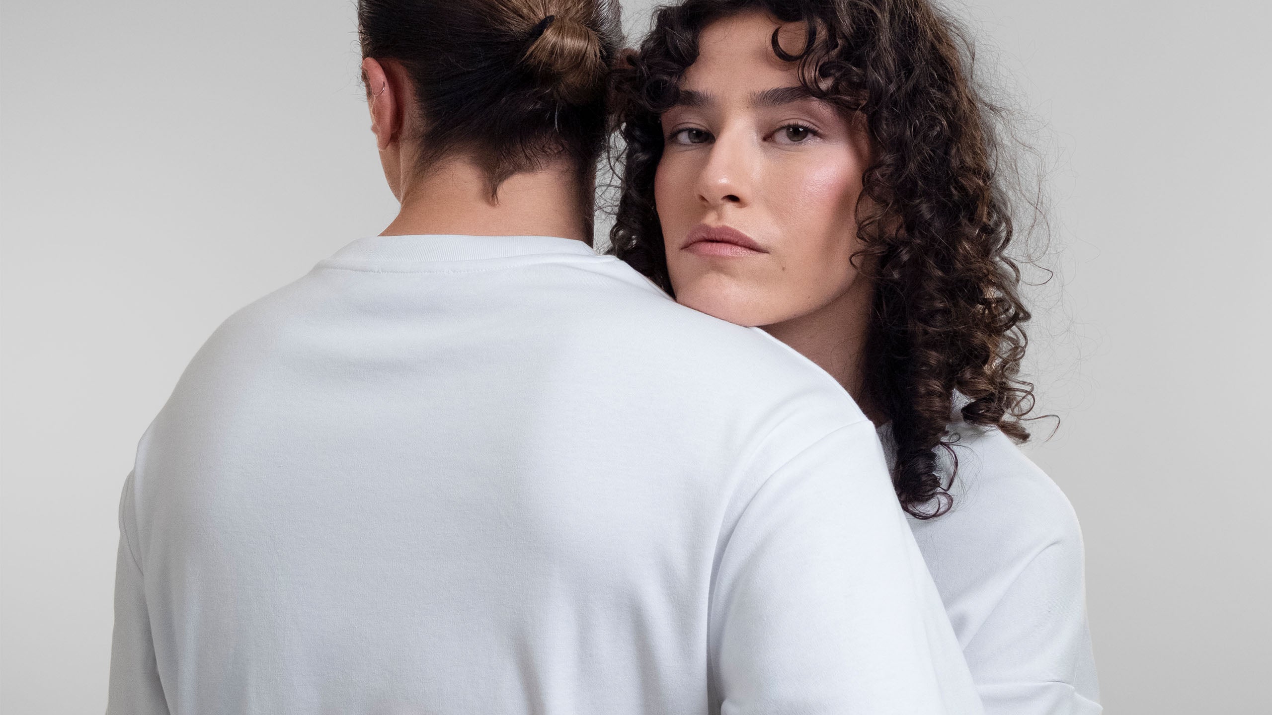 Two models hugging each other and wearing Open Row's signature Open Heart t-shirt in white.