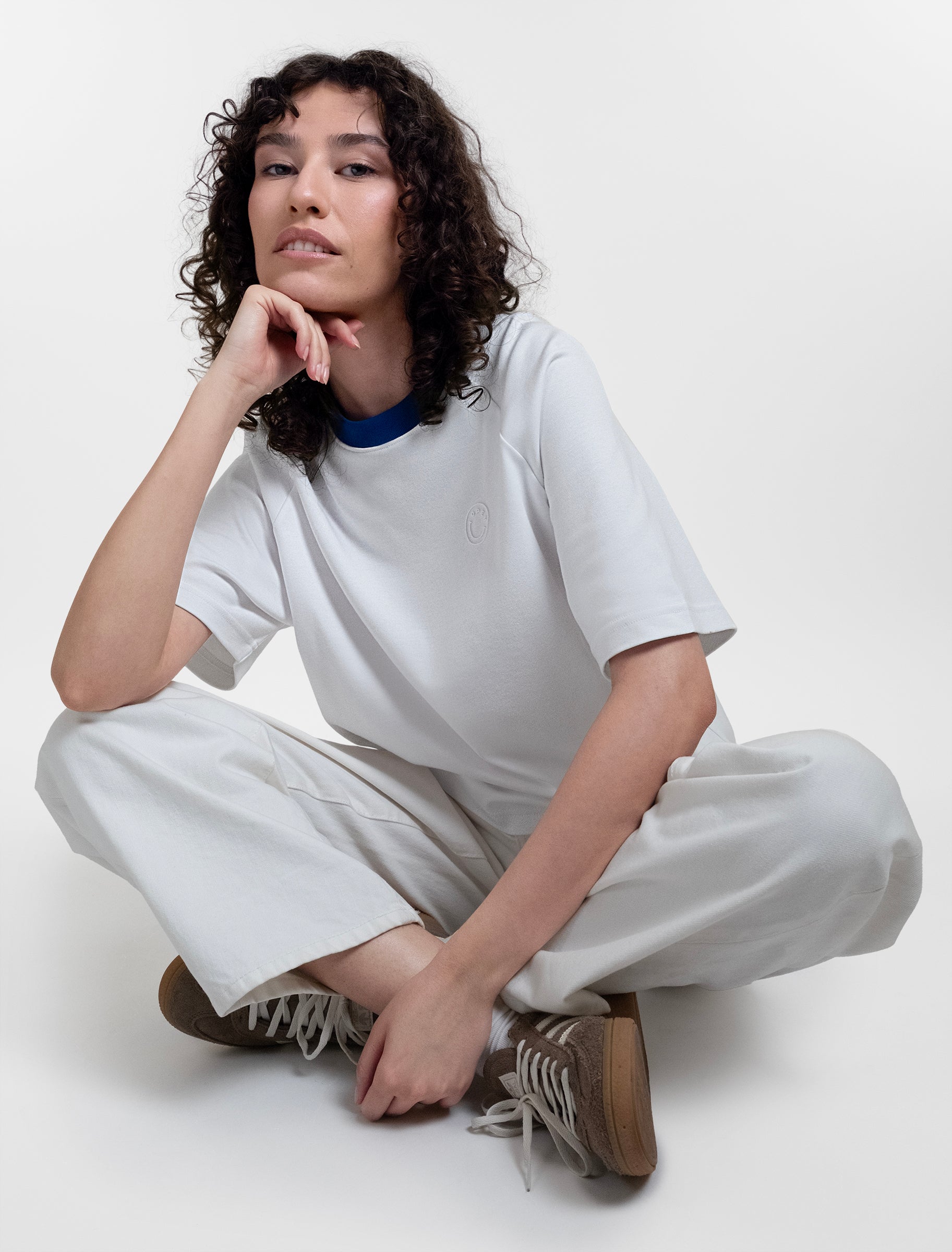 Open Row Women's Runaway Tee in white with blue collar, editorial view paired with white pants.